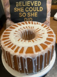 a bundt cake sitting on top of a white plate next to a sign that says, i believe she could so she did