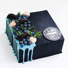 a cake decorated with berries and blueberries on top of a black piece of paper