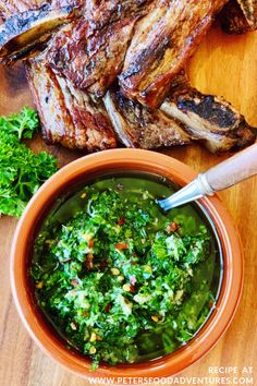 steaks and greens in a bowl on a wooden table next to a small bowl of sauce