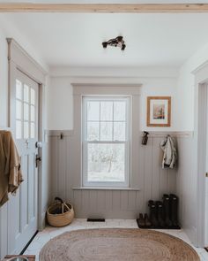 a room with a rug, window and coat rack on the wall next to it