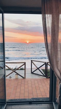 the sun is setting over the ocean as seen from an open door