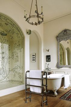 a bath tub sitting next to a white sink in a bathroom under a chandelier