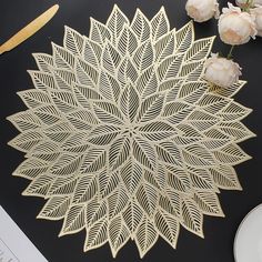 an intricately designed paper doily sits on a table next to flowers and scissors