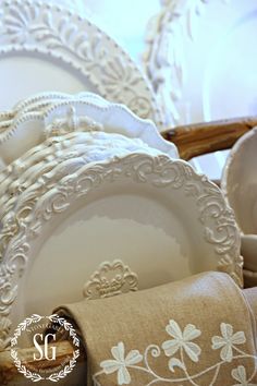 white plates and napkins are stacked on top of each other in an ornate basket