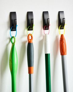 four different colored pens are lined up on the wall next to each other with hooks