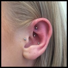 a woman's ear with three piercings on it