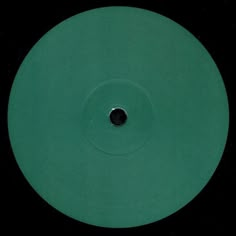 a close up of a green disc on a black surface with a hole in the center