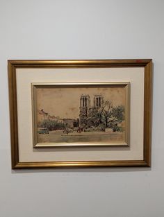 a painting hanging on the wall in front of a white wall with a gold frame