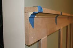 a piece of blue tape is taped to the edge of a fireplace mantel with wooden slats