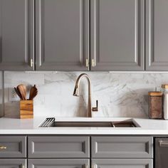 a kitchen with gray cabinets and marble counter tops