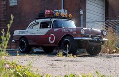 an old car is parked in front of a building