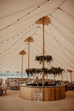 the inside of a tent with tables, chairs and lights on it's ceiling