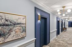 an empty hallway with blue doors and paintings on the wall next to eachother