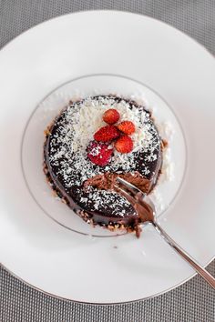 a piece of chocolate cake with strawberries on top and powdered sugar on top