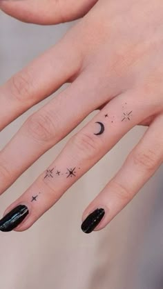 a woman's hand with stars and moon tattoos on it, while the fingers are black