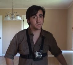 a man standing in a room with a camera around his neck