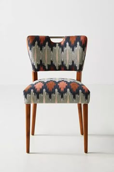 an upholstered chair with wooden legs and patterned fabric