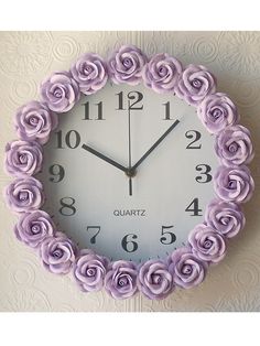 a clock made out of purple roses on a wall