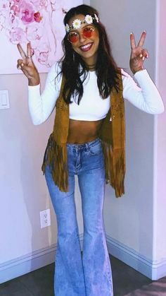 a woman in jeans and a white top is posing for the camera with her peace sign