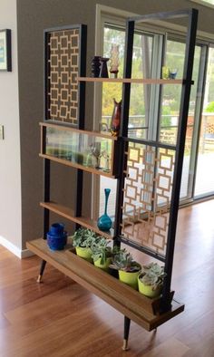 a shelf filled with pots and plants on top of a hard wood floor