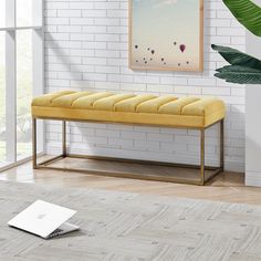 a yellow bench sitting in front of a white brick wall