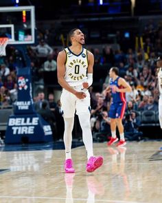 a basketball player is walking on the court with his feet in the air and people watching