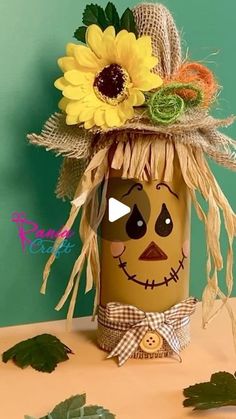 a scarecrow jar with sunflowers and leaves on the top, sitting on a table