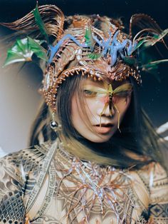 a woman with an elaborate headdress on her face and body is shown from the shoulders down