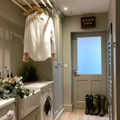 a washer and dryer in a laundry room next to a door with clothes hanging on it