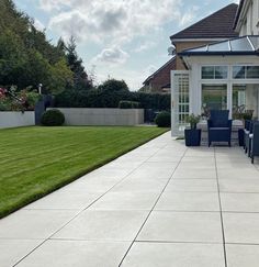 a patio with chairs and tables in front of a house