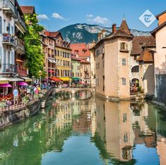 a river running through a small town next to tall buildings with umbrellas on them