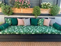 a green couch sitting on top of a wooden floor next to potted planters