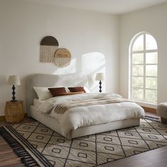 a bedroom with a large bed and two lamps on either side of the bed in front of an arched window