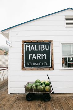 there is a sign that says malbu farm and some watermelons in front of it