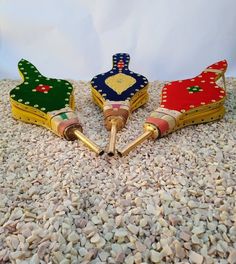 three small wooden toys sitting on top of gravel