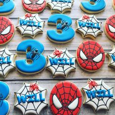 decorated cookies are arranged in the shape of numbers and spider - man symbols on a table