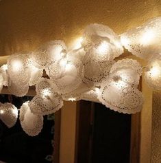 some lights are hanging from the ceiling in front of a mirror with flowers on it