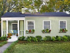 a small green house with some plants on the front and windows in the back yard