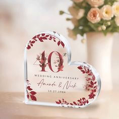 a heart shaped acrylic with the number forty on it and flowers in the background