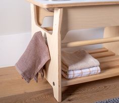 a wooden shelf with folded towels and a towel rack on the floor next to it