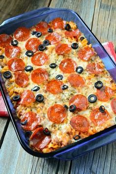 a pizza casserole with pepperoni and olives in a blue dish on a wooden table