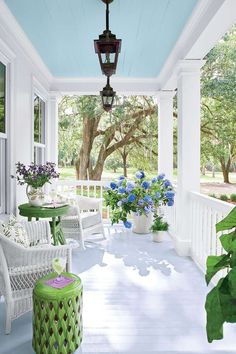 an image of a porch with white furniture and green plants on the front porch area