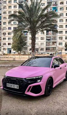 a pink car parked in front of a palm tree