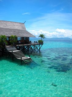 a house on stilts in the middle of clear blue water