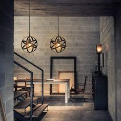 an industrial style dining room with two pendant lights hanging from the ceiling and stairs leading up to the second floor