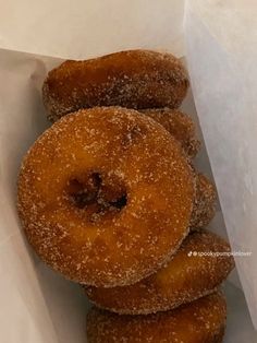 a pile of doughnuts sitting inside of a white paper bag filled with powdered sugar