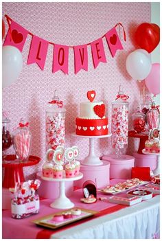 a table topped with lots of pink and red desserts next to balloons in the shape of hearts