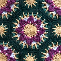 a crocheted blanket is shown with flowers on the top and bottom, in shades of green, purple, yellow and white