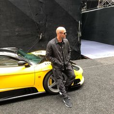 a man standing next to a yellow sports car