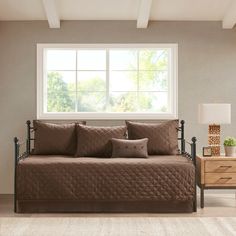 a bedroom with a daybed and two nightstands in front of a large window